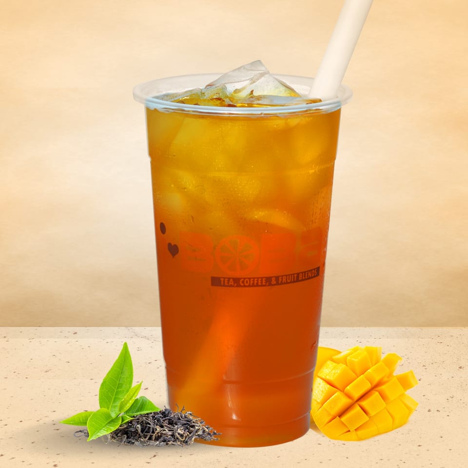I HEART BOBA FM 529 mango iced tea with ice, a straw, tea leaves, and diced mango.
